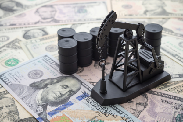 Produção de petróleo Miniatura de bomba envolvida em extração de petróleo sobre notas de dólar.